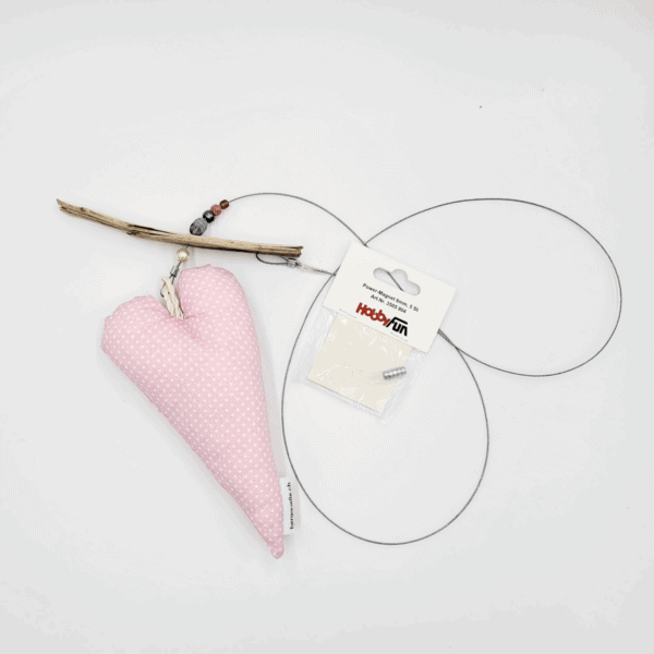Die „Fotoleine mit Herz“ zeigt ein rosa gepunktetes Herzornament aus Treibholz und Draht, das neben einem Paket mit der Aufschrift „Happy Fun“ ruht.