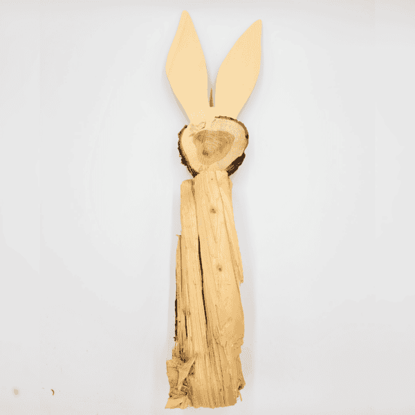 Der Hase ist eine aus Baumrinde und Baumstämmen gefertigte Holzskulptur eines stehenden Kaninchens mit langen Ohren.