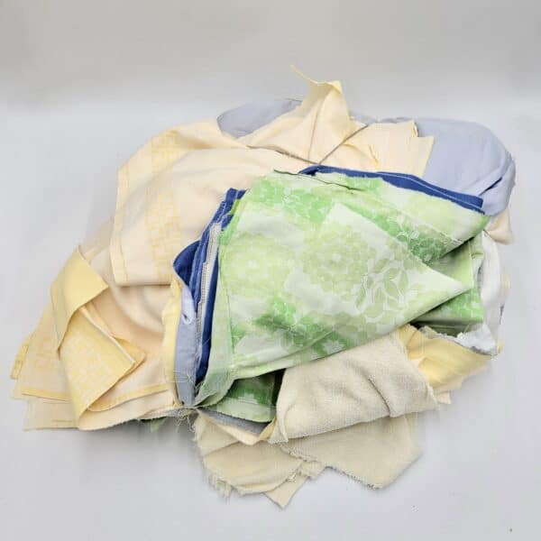 Eine Sammlung von Putzlappen-Stoffresten in Pastelltönen wie Grün, Blau und Gelb mit verschiedenen Mustern.